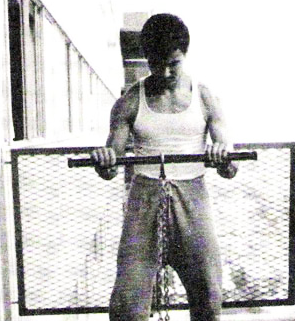 Bruce Lee working performing a bicep curl exercise