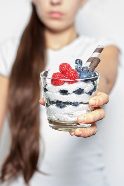 Девушка держит в руке стакан с мороженным и ягодами